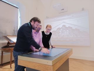 Guide giving tour to two visitors within interior exhibition of the Custom House